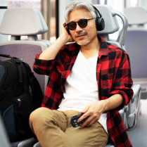 Lecteur audio et dictaphone Victor Reader Stream 3 utilisation par un homme avec un casque dans un train