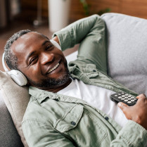 Lecteur audio et dictaphone Victor Reader Stream 3 utilisation par un homme allongé sur un canapé avec un casque